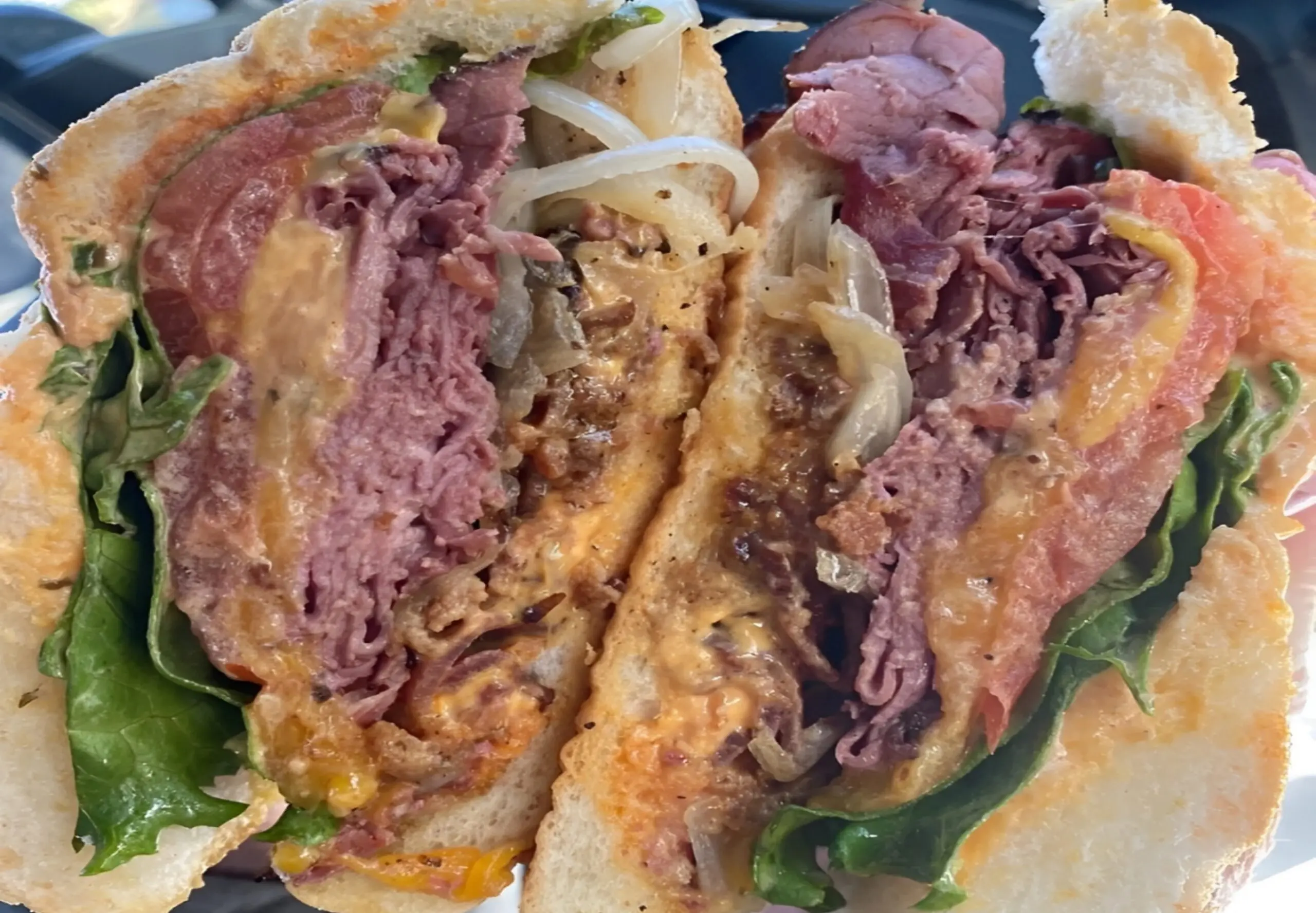 Hearty sandwich with meat, lettuce, and onions.