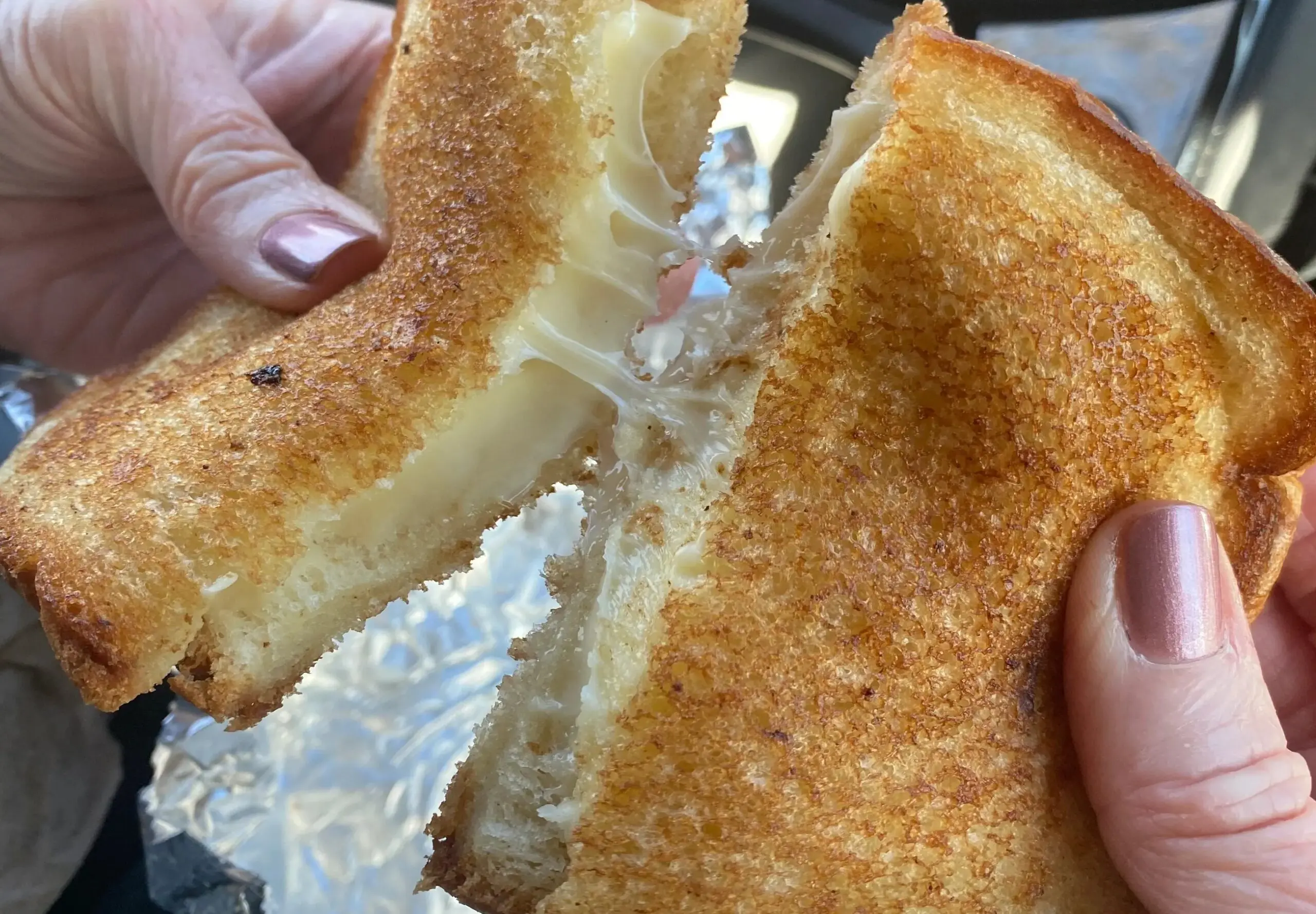 Hands holding a grilled cheese sandwich.