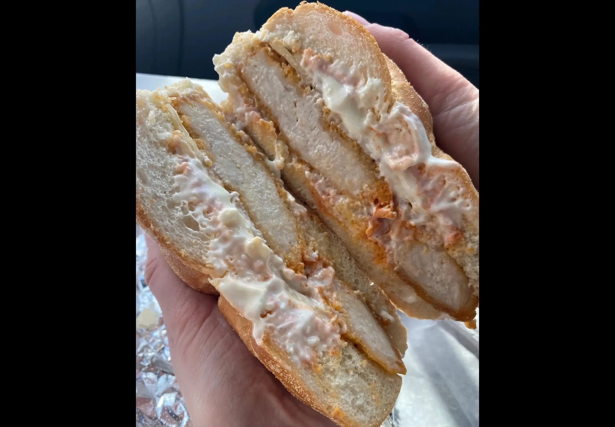 Chicken sandwich with creamy sauce held up.