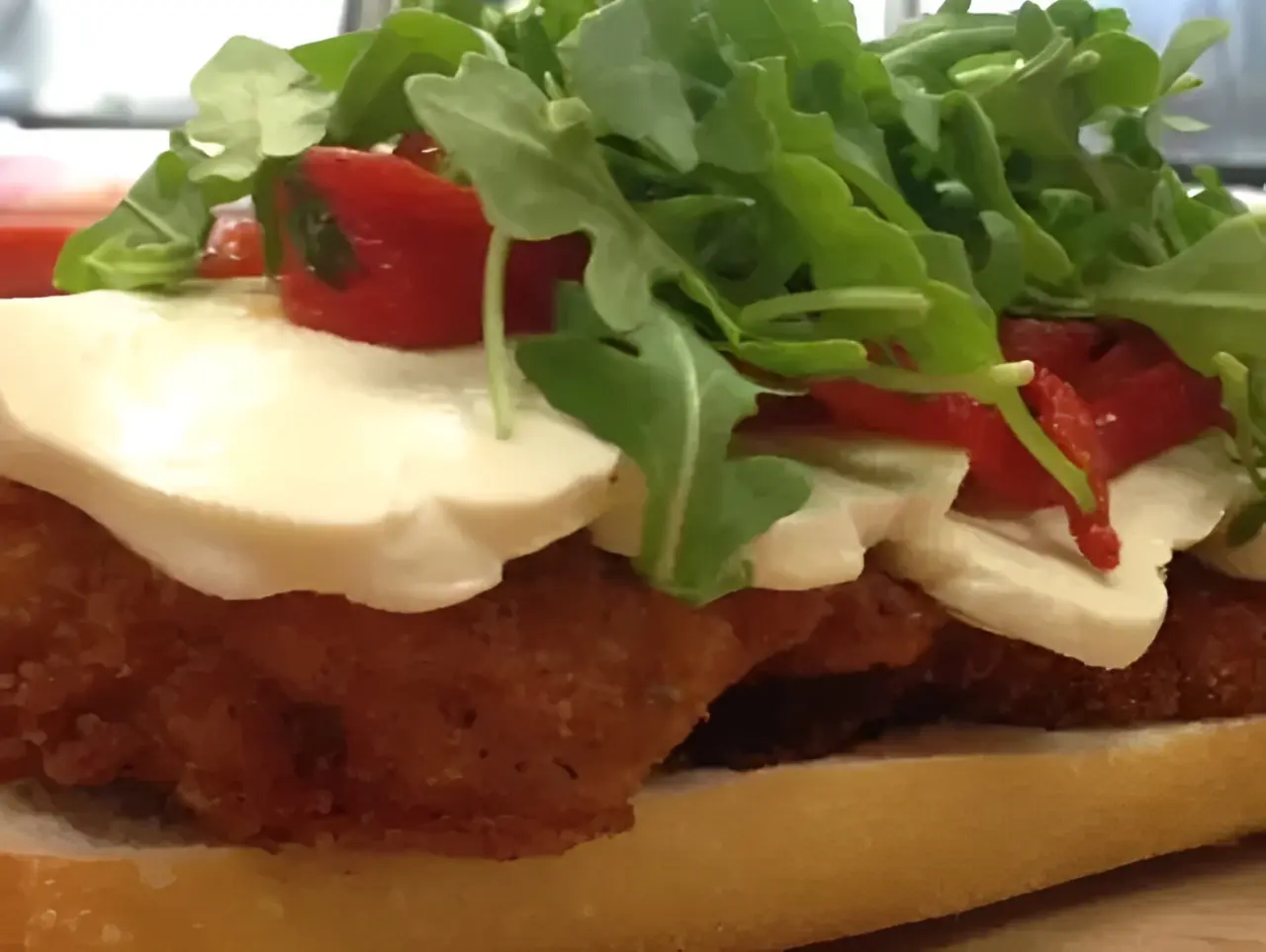 Chicken sandwich with arugula and mozzarella cheese.